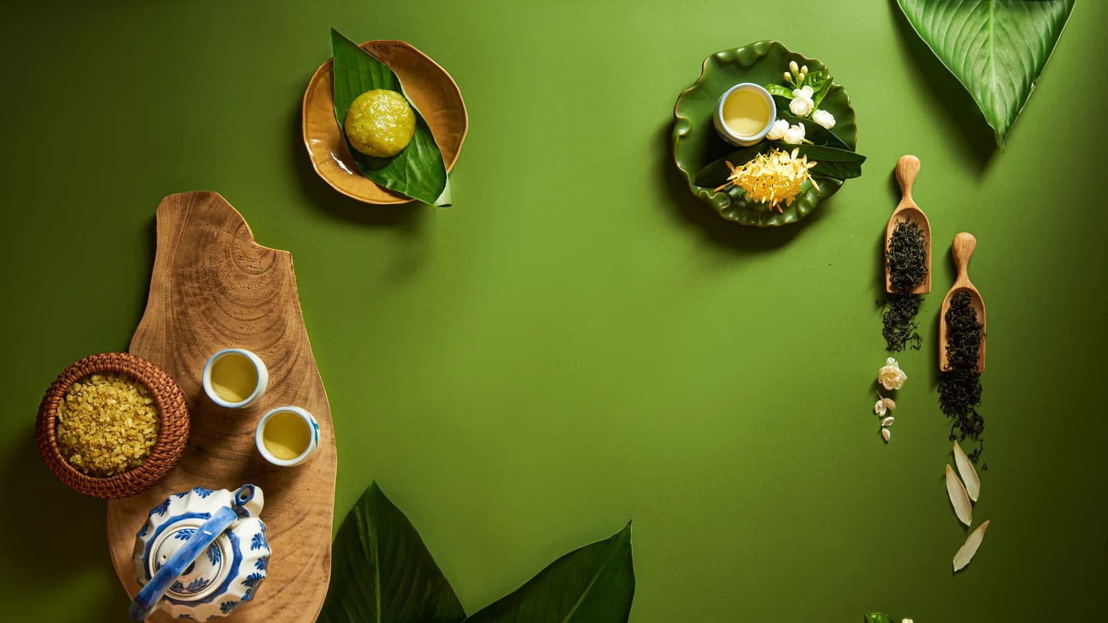Bánh xanh, cốm và bộ ấm chén bày trên nền xanh lá